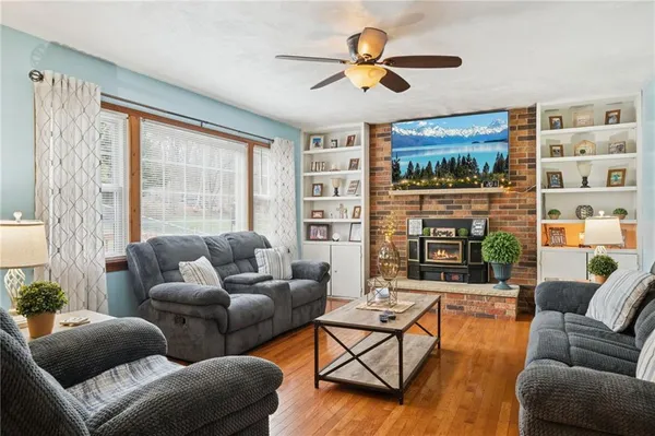 a living room with furniture ceiling fan and a large window