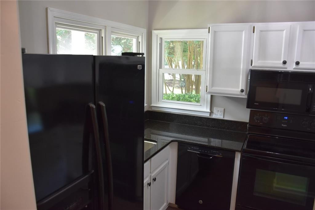 4466 Roller Court Raleigh, NC 27604 - Photo 6 of 12 a kitchen with granite countertop white cabinets and black appliances