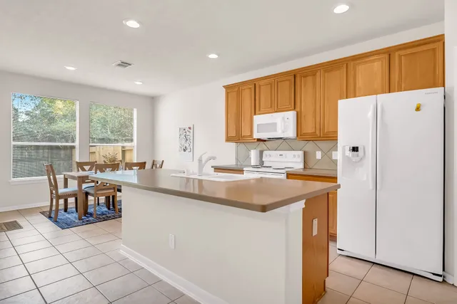 a kitchen with stainless steel appliances granite countertop a refrigerator a sink a stove and white cabinets with wooden floor