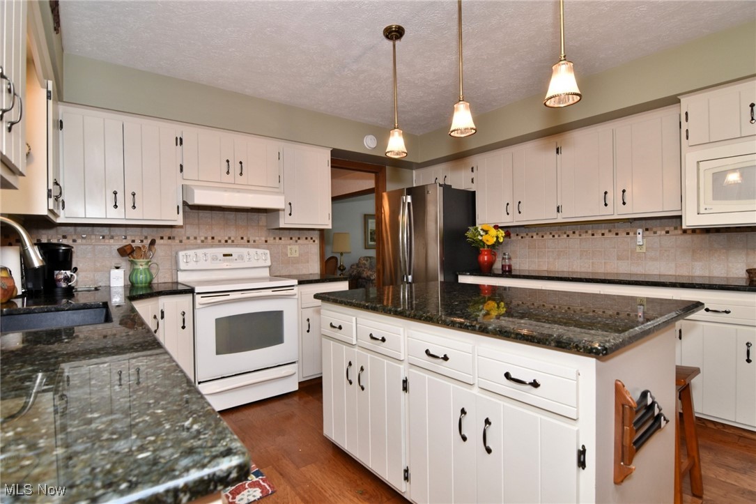 5510 Som Center Road Solon, OH 44139 - Photo 6 of 38 Kitchen featuring white appliances, under cabinet range hood, a sink, a kitchen island, and tasteful backsplash