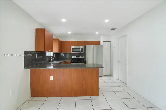 a kitchen with stainless steel appliances granite countertop a refrigerator and a stove top oven