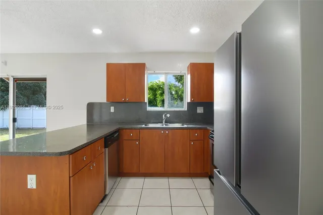 a kitchen with stainless steel appliances granite countertop a sink and a refrigerator
