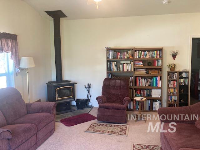 1095 County Road 70 Weiser, ID 83672 - Photo 14 of 44 Living area featuring a freestanding wood-burning stove with a gold-tone trim, a visible flue, and a protective hearth