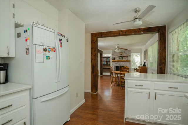 a white kitchen with stainless steel appliances a refrigerator and a stove top oven