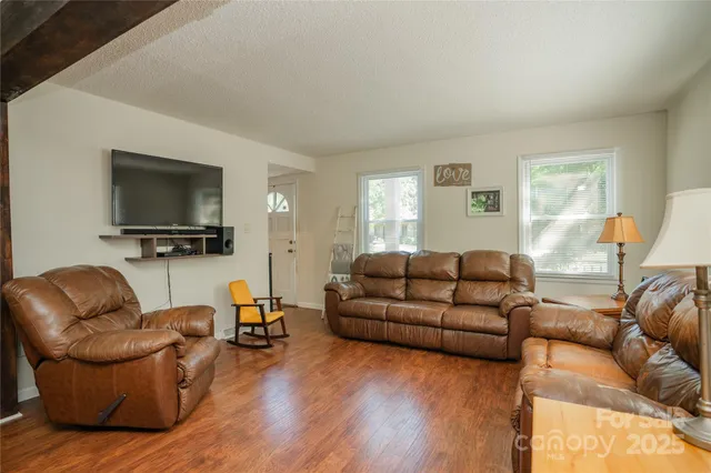 a living room with furniture a flat screen tv and wooden floor