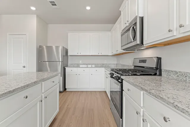 a kitchen with stainless steel appliances granite countertop a stove a sink and a refrigerator
