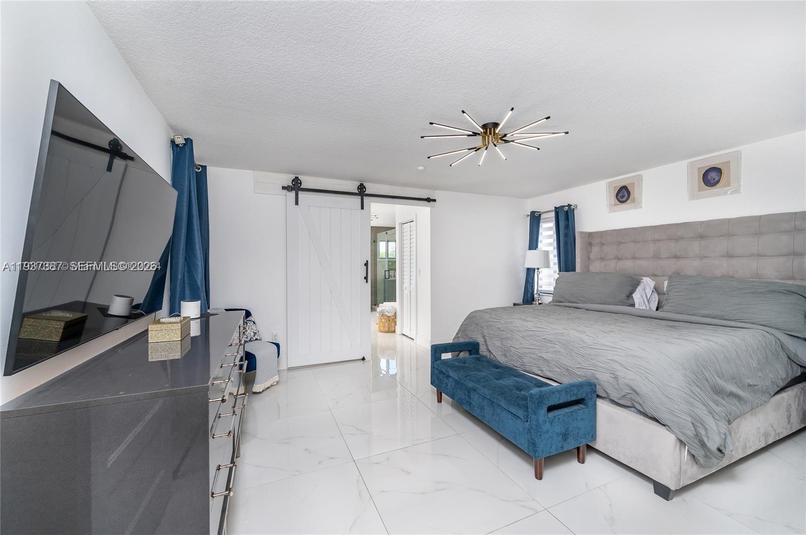9701 Southwest 56th Terrace Miami, FL 33173 - Photo 32 of 48 a spacious bedroom with a bed a dresser and a large mirror