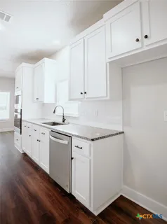 a kitchen with granite countertop white cabinets and white appliances