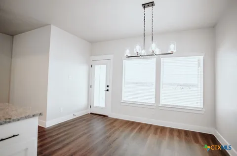 a view of empty room with wooden floor fan and window
