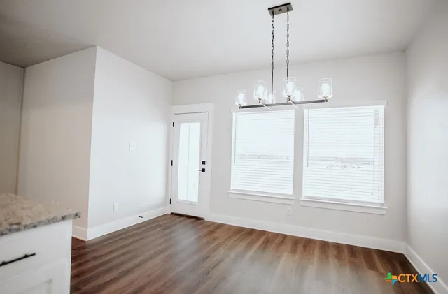 a view of empty room with wooden floor fan and window