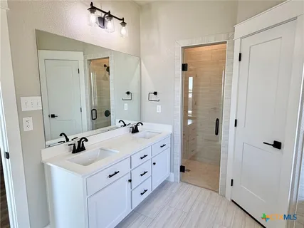 a bathroom with a double vanity sink a mirror and a shower