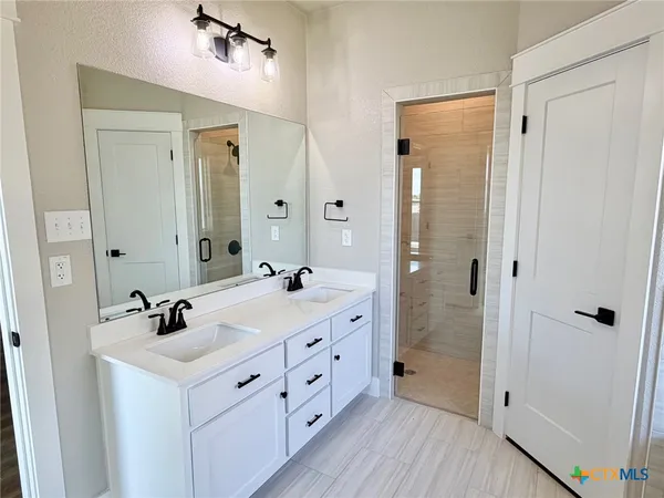 a bathroom with a double vanity sink a mirror and a shower