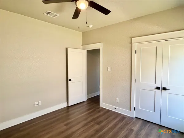 an empty room with wooden floor closet and windows