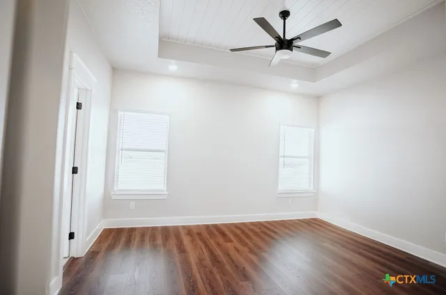 an empty room with wooden floor and windows