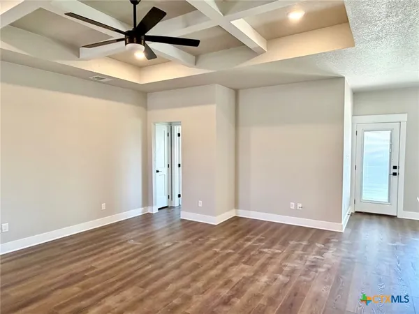 an empty room with wooden floor and fan