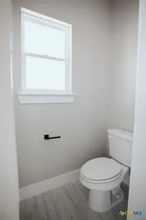 a white toilet sitting in a bathroom next to a window