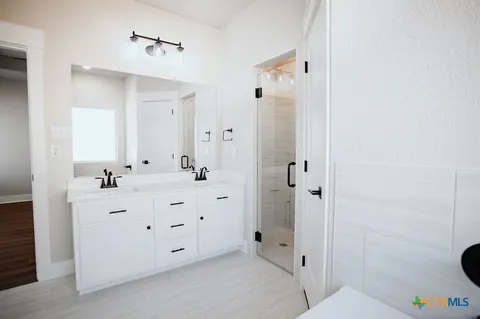a bathroom with a double vanity sink mirror and shower