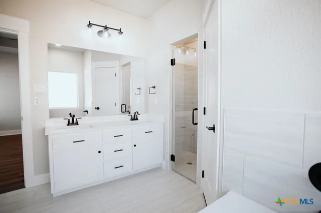a bathroom with a double vanity sink mirror and shower