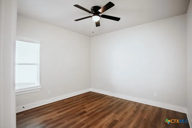 a view of a room with wooden floor and a ceiling fan