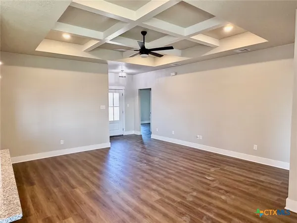 an empty room with wooden floor ceiling fan and windows