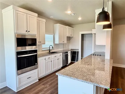 a kitchen with stainless steel appliances granite countertop a stove a sink and a refrigerator