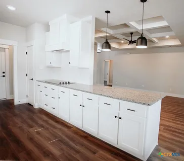 a kitchen with granite countertop white cabinets and a wooden floor