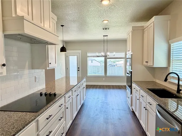 a kitchen with stainless steel appliances kitchen island wooden floors granite counter tops and a window