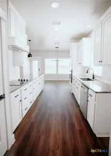 a kitchen with granite countertop a sink cabinets and wooden floor