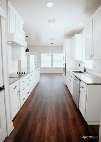 a kitchen with granite countertop a sink cabinets and wooden floor