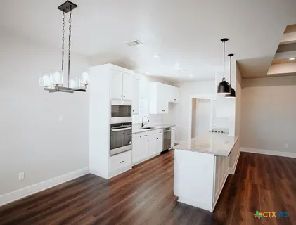 a kitchen with stainless steel appliances a stove top oven a sink and cabinets