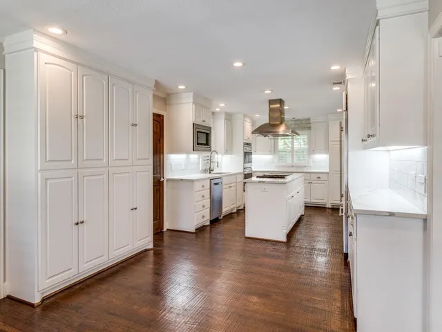 a kitchen with kitchen island white cabinets and stainless steel appliances