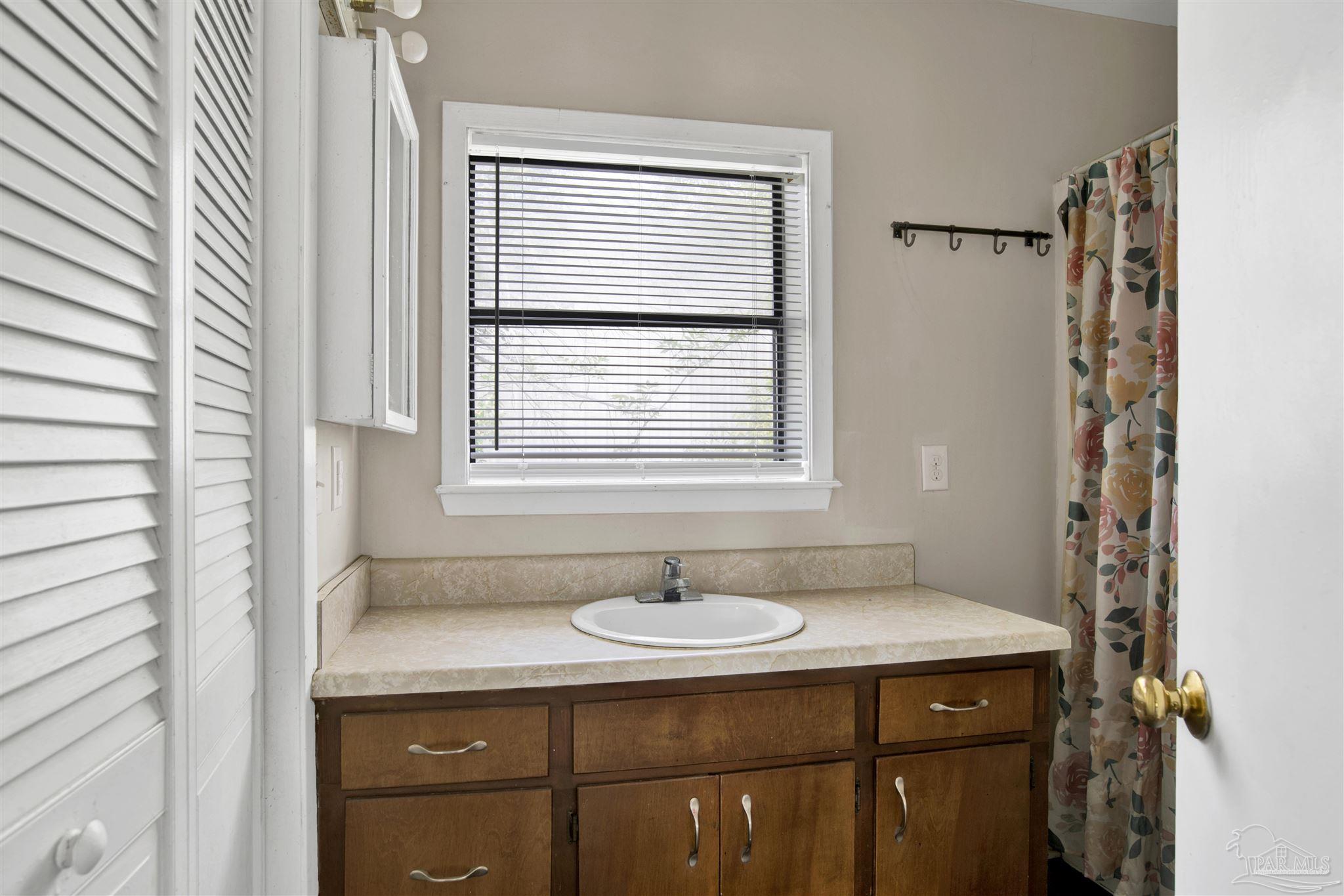 2802 West Gonzalez Street Pensacola, FL 32505 - Photo 14 of 24 a bathroom with a sink a vanity and a mirror