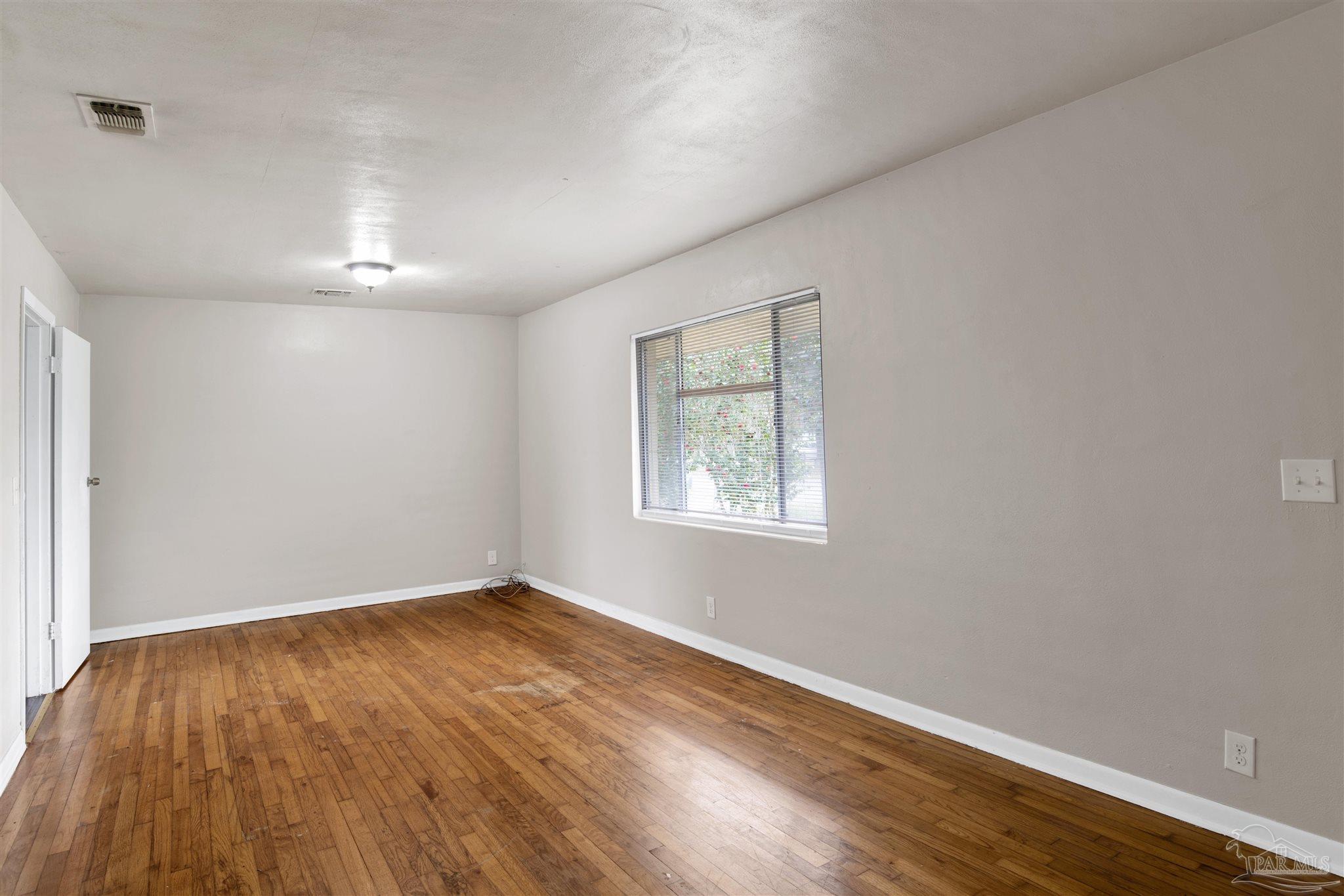 2802 West Gonzalez Street Pensacola, FL 32505 - Photo 5 of 24 an empty room with wooden floor and windows