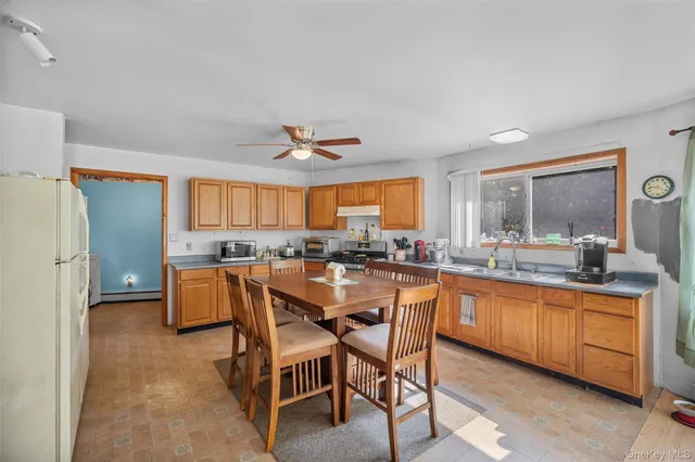 a dining hall with stainless steel appliances granite countertop a sink a stove a dining table and chairs