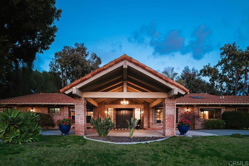 a view of a house with a yard potted plants and a large tree