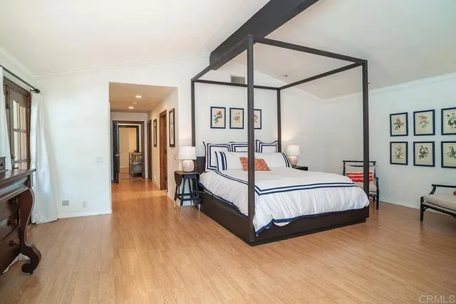 a bedroom with a bed a mirror and a bookshelf with wooden floor
