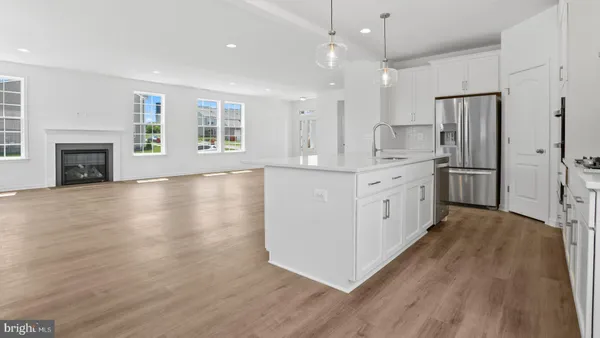 a large kitchen with stainless steel appliances granite countertop a refrigerator a oven a fireplace and a stove with wooden floors