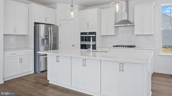 a kitchen with stainless steel appliances white cabinets and wooden floors