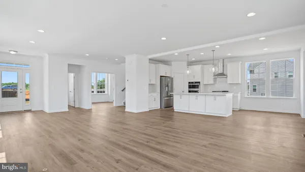 a kitchen with stainless steel appliances kitchen island granite countertop a stove a sink a refrigerator and white cabinets with wooden floor