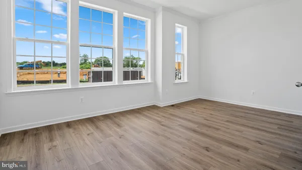 an empty room with wooden floor fireplace and windows