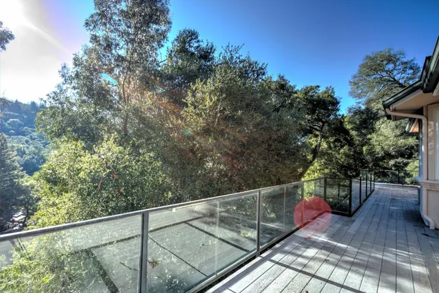 a balcony with wooden floor and trees in the background