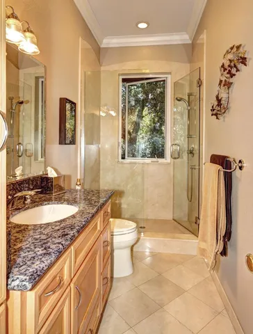 a bathroom with a granite countertop sink a toilet a mirror and shower