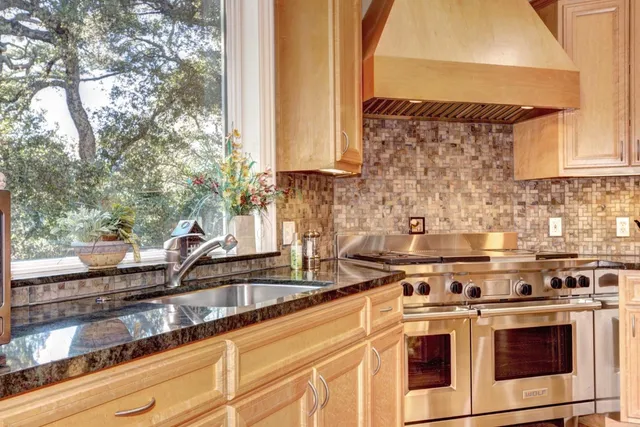 a kitchen with granite countertop a sink a stove and cabinets