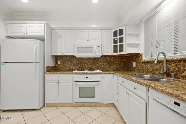 a kitchen with granite countertop white cabinets and refrigerator