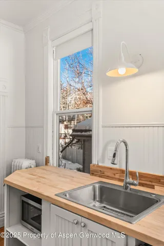 a view of a white house with a yard plants and large tree
