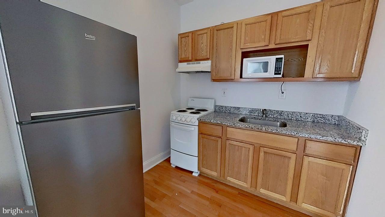 1234-40 Rising Sun Avenue, Unit D Philadelphia, PA 19140 - Photo 5 of 11 a kitchen with stainless steel appliances granite countertop a refrigerator a microwave oven with white cabinets