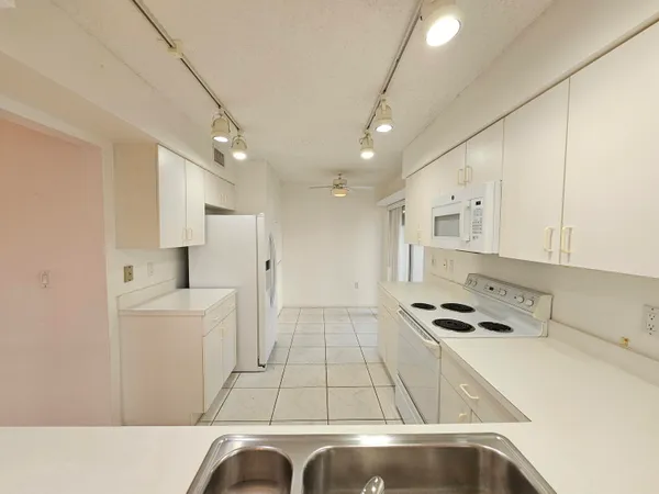 a kitchen with stainless steel appliances a refrigerator a sink and white cabinets