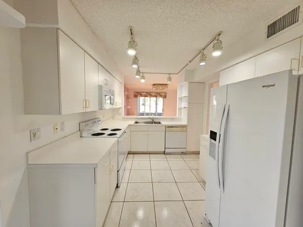 a kitchen with white cabinets and white appliances