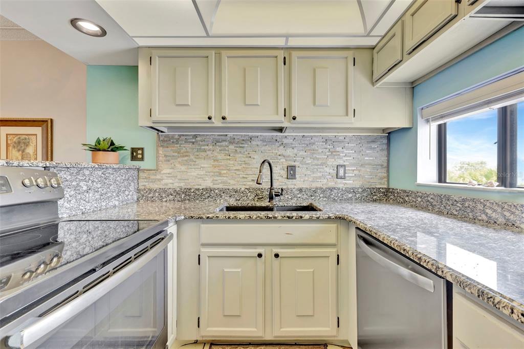 6157 Midnight Pass Road, Unit E24 Sarasota, FL 34242 - Photo 21 of 44 a kitchen with stainless steel appliances granite countertop a sink stove and cabinets