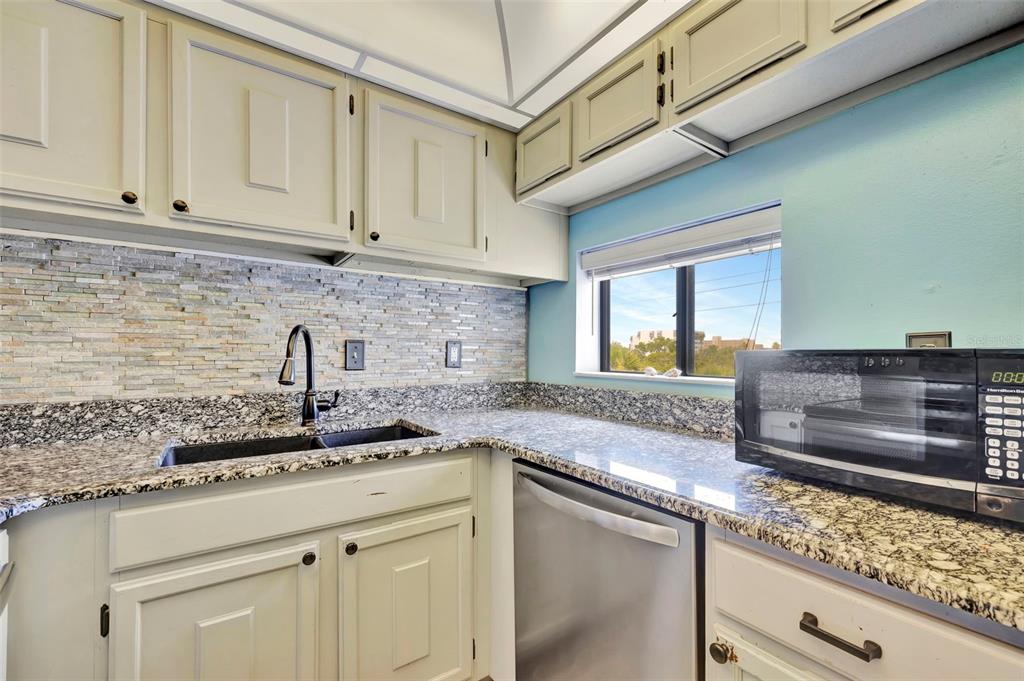 6157 Midnight Pass Road, Unit E24 Sarasota, FL 34242 - Photo 22 of 44 a kitchen with stainless steel appliances granite countertop a sink and cabinets